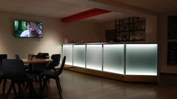 A modern bar area with a counter, chairs, and a TV screen.