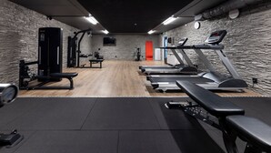 Ett gym med löpband, en bänkpress och styrketräningsmaskiner.