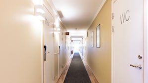 A hotel hallway with doors numbered 116 and 117, a WC sign, and framed pictures on the walls. - Good Morning Lund (Lund)