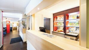 A hotel reception area with a wooden reception desk, a clock, and a bar stocked with beverages. - Good Morning Lund (Lund)