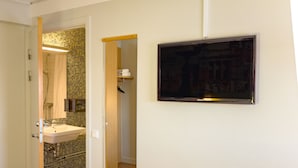 A room with two beds, a bathroom with a shower, and a mounted television. - Good Morning Lund (Lund)