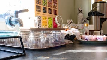 Un angolo caffè con una macchina da caffè, un vassoio di tazze e una selezione di cialde.