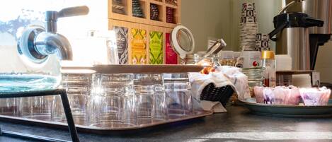Un espace dédié au café, comprenant une machine à café, un plateau de tasses et un présentoir de dosettes de café.