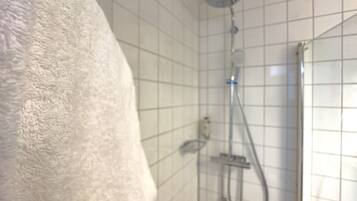 A bathroom with a shower, tiled walls, and a towel hanging on the wall.