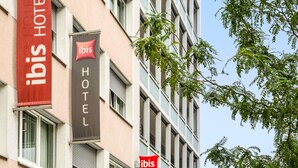 A building with two banners, one red and one black, both displaying the 'ibis HOTEL' logo. - ibis Geneve Centre Gare (Geneva)