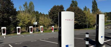 En parkeringsplats med flera laddstationer för elbilar av märket Tesla.