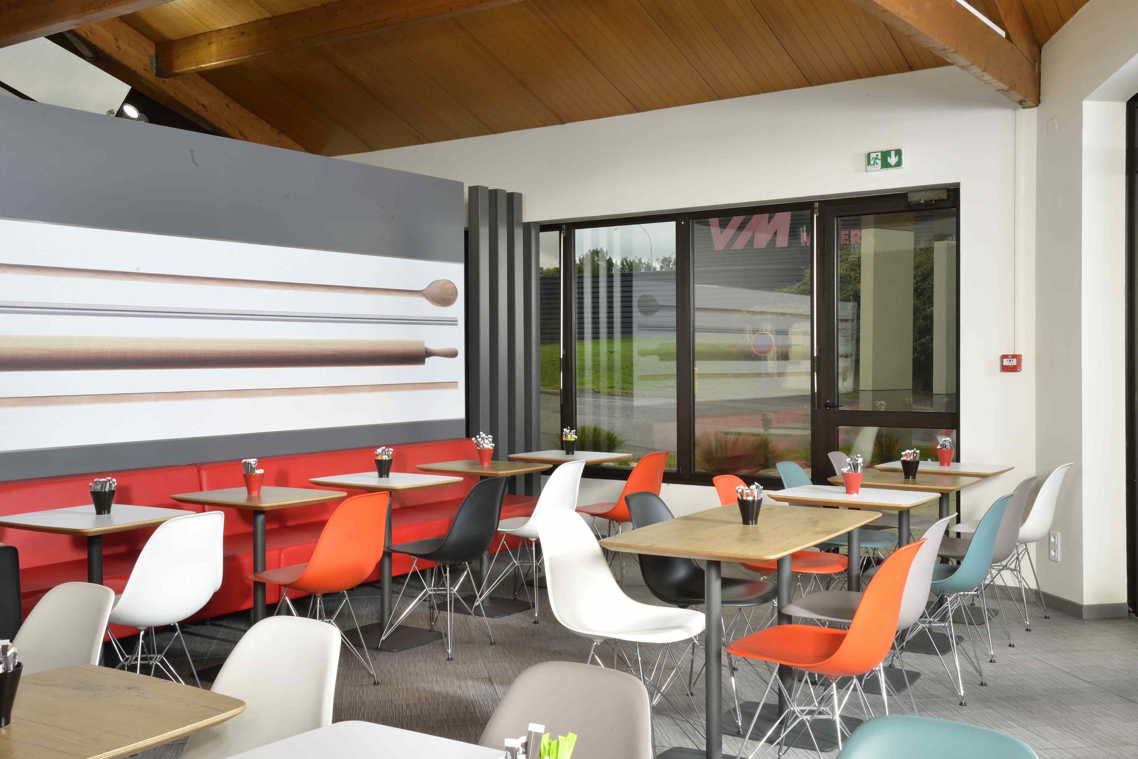 A modern dining area with tables and chairs, a large abstract art piece on the wall, and a view through the glass door.