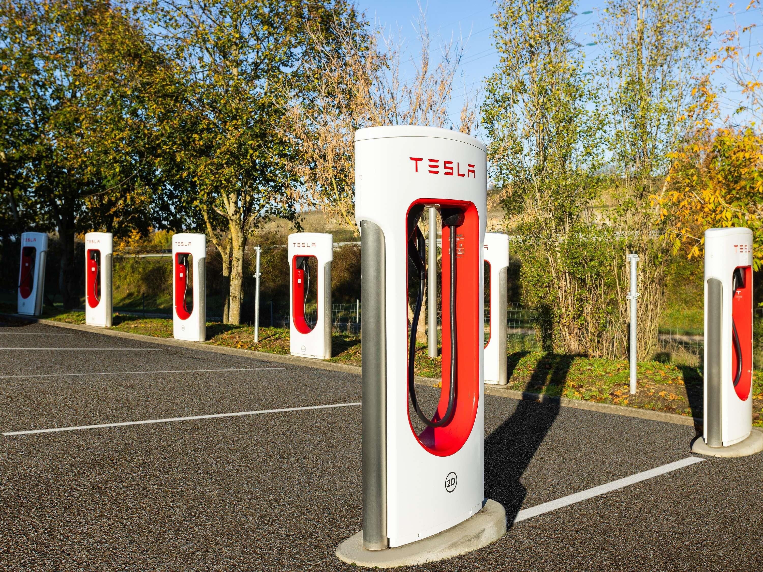Una fila de estaciones de carga para vehículos eléctricos Tesla en un estacionamiento.