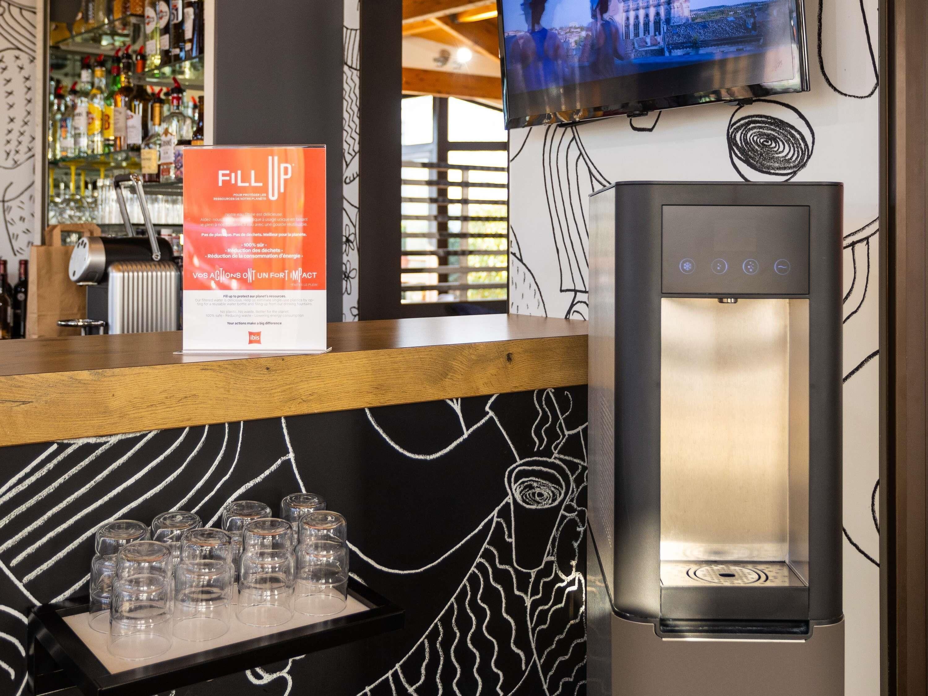 A bar area with a water dispenser and glasses on the counter.