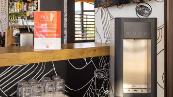 A bar area with a water dispenser and glasses on the counter.