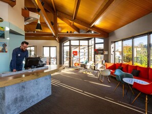 A modern interior with a reception desk, seating area, and large windows. - ibis Angouleme Nord (Champniers)