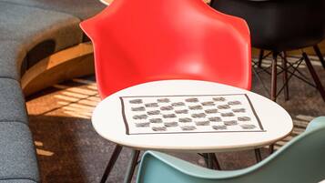 Un espace salon avec une table ronde, une chaise rouge et une chaise de couleur turquoise.