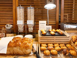 A bakery display with bread, pastries, and labeled containers of ingredients. - ibis Angouleme Nord (Champniers)