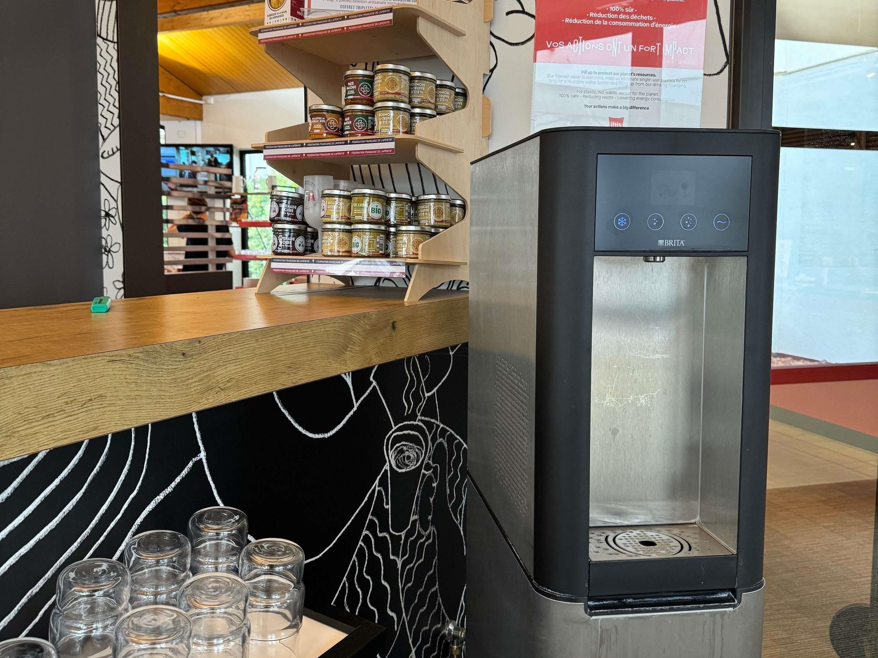 Een moderne keuken met een roestvrijstalen koelkast, een houten aanrecht met potten en een wand bedekt met een schoolbord.