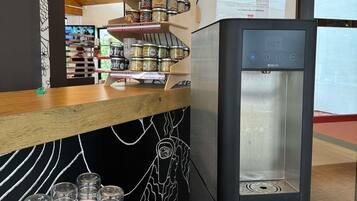 Un área de cocina moderna con un refrigerador de acero inoxidable, una encimera de madera con frascos y una pared de pizarra.