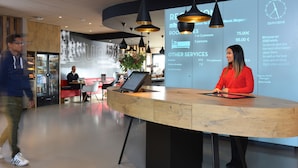 Un mostrador de recepción de hotel con una pantalla digital que muestra tarifas y servicios.