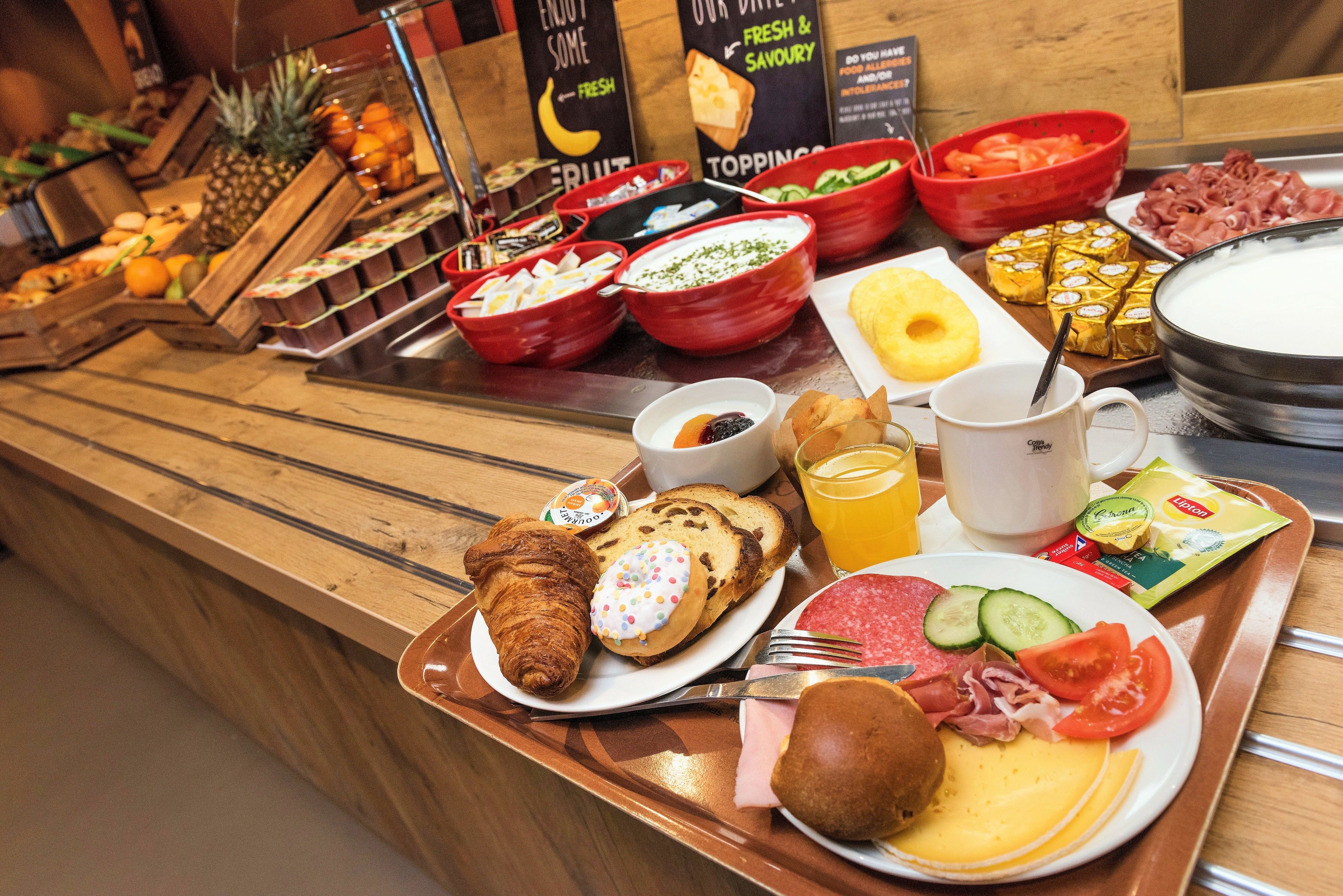 Un bufé con diversos alimentos, entre ellos frutas, quesos, carnes y pasteles.