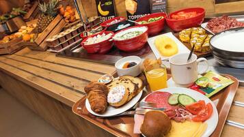 Un bufé con diversos alimentos, entre ellos frutas, quesos, carnes y pasteles.