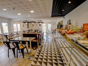 A restaurant with a checkered floor, tables, chairs, a buffet area, and artwork on the walls. - ibis Haguenau Strasbourg Nord (Haguenau)