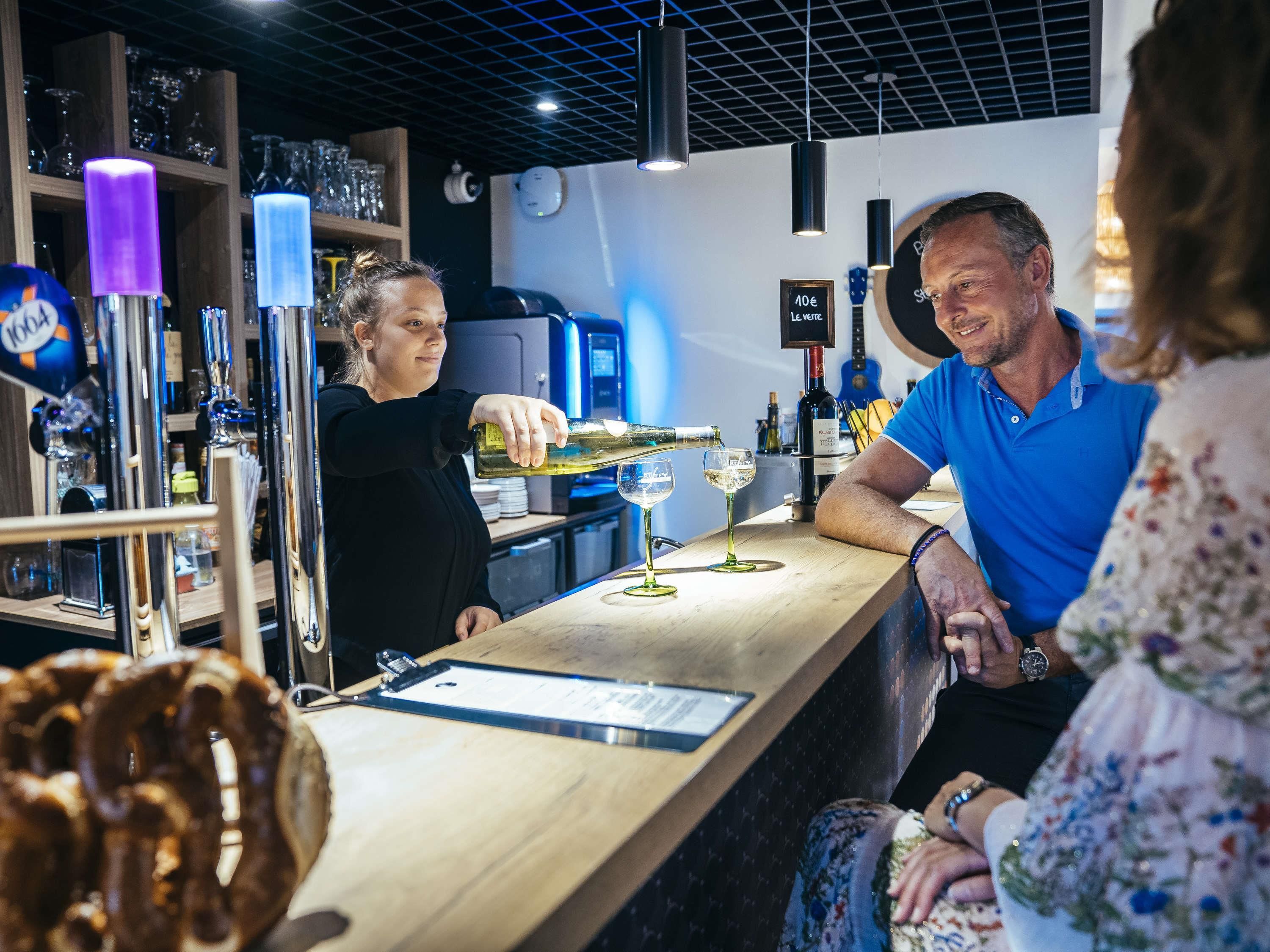 A bar area with a counter, glasses, and a menu.
