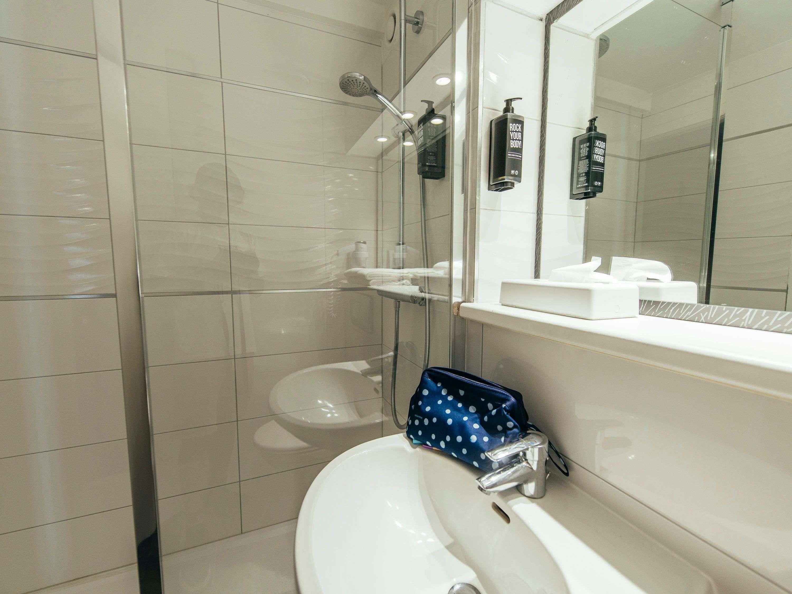 A modern bathroom with a glass shower enclosure, a white sink, and a mirror above the sink.
