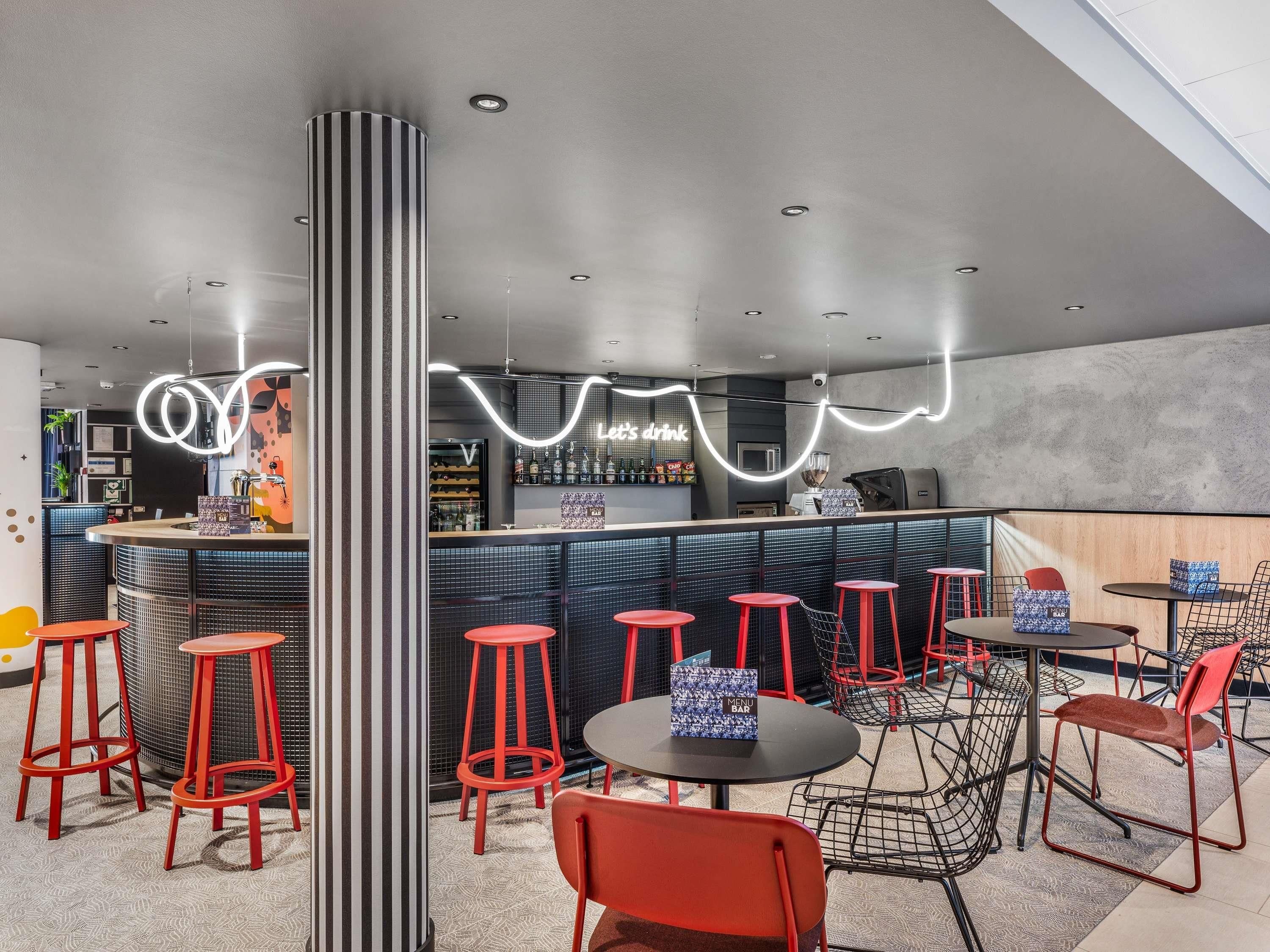 Un área de bar moderna con mostrador, taburetes y mesas.
