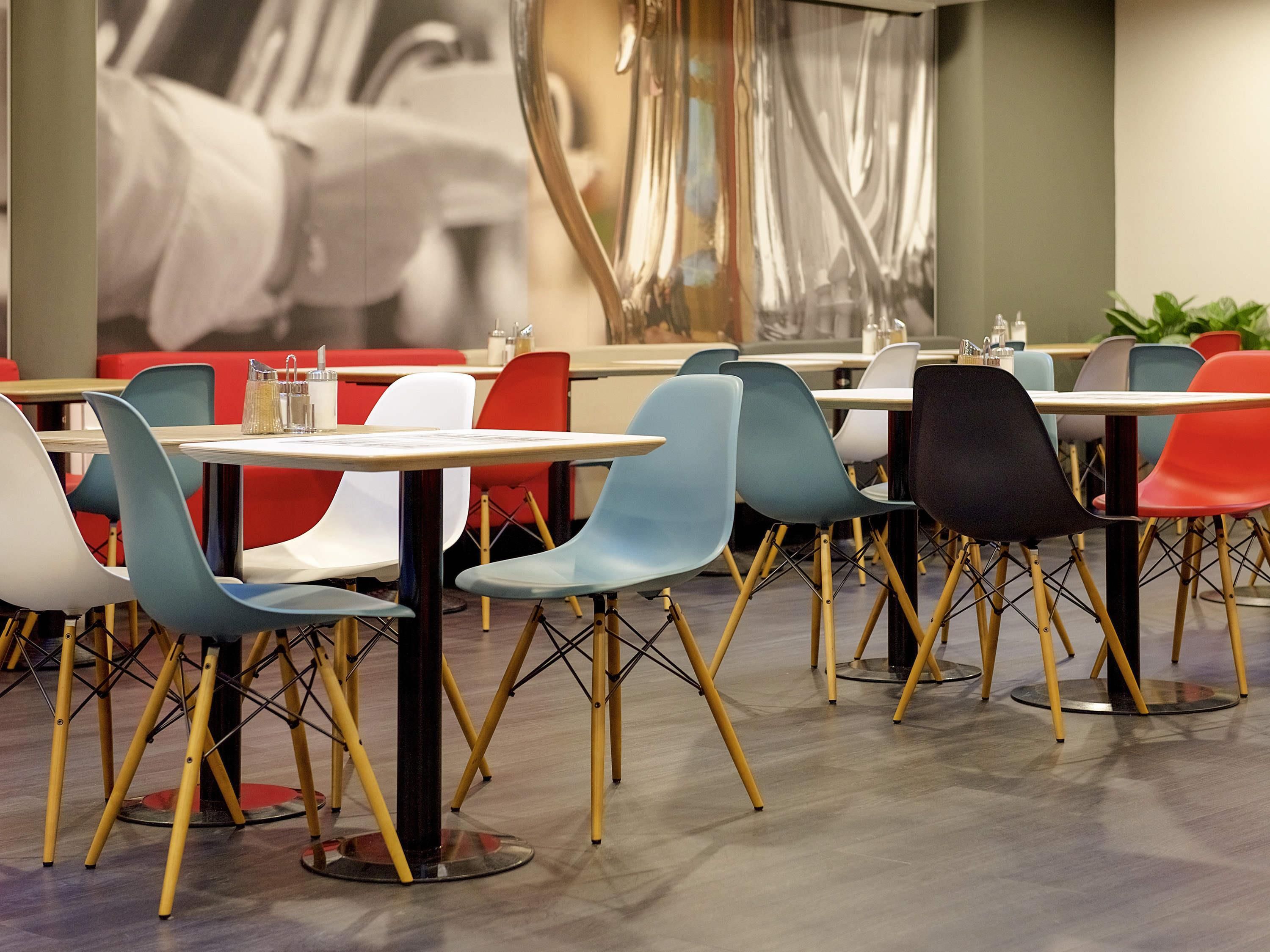Un comedor moderno con varias mesas y sillas, que destaca por una mezcla de colores y un diseño contemporáneo.