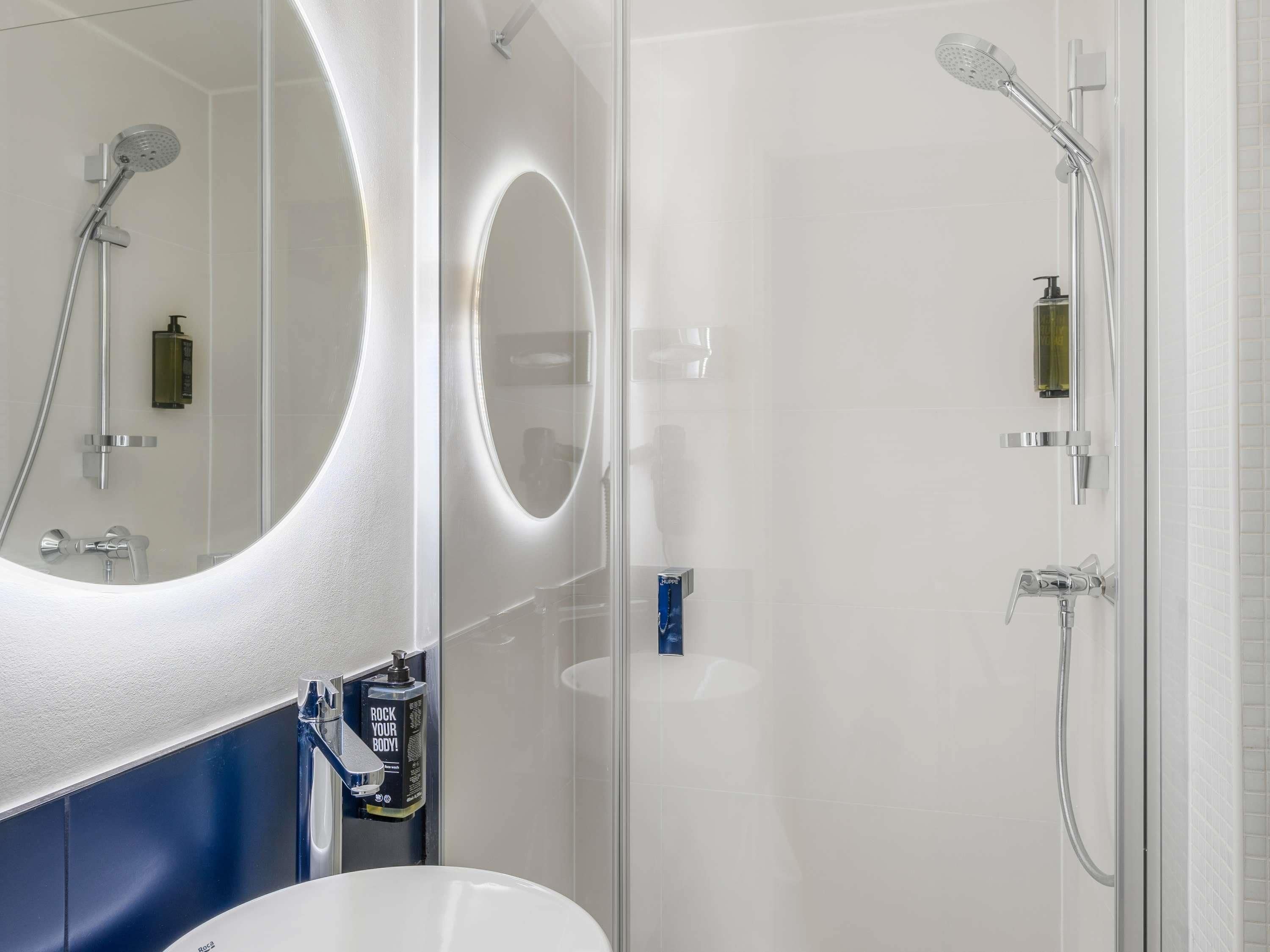 Un baño moderno con un espejo grande, ducha y lavabo.