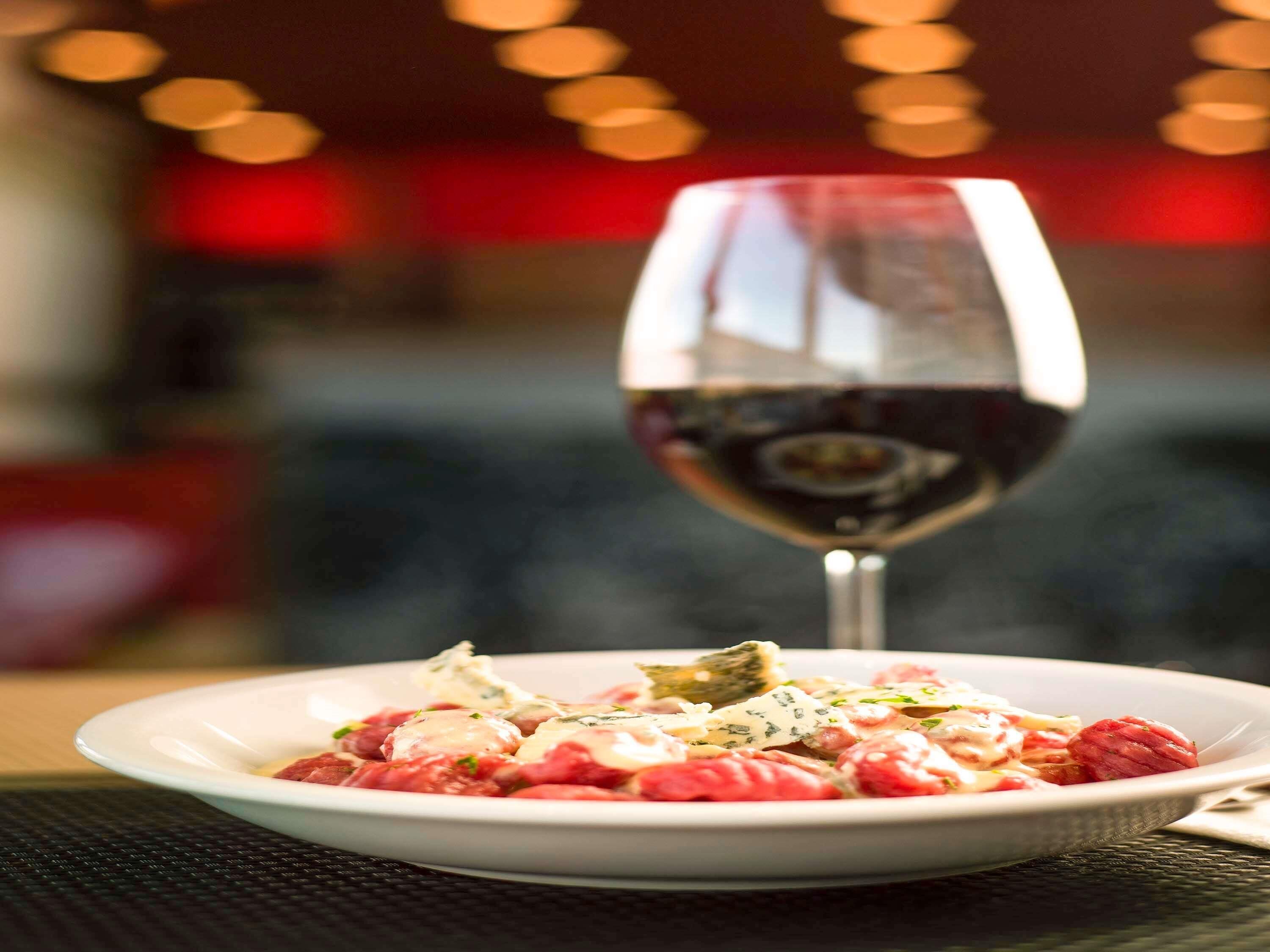 Un plato de comida con una copa de vino tinto.