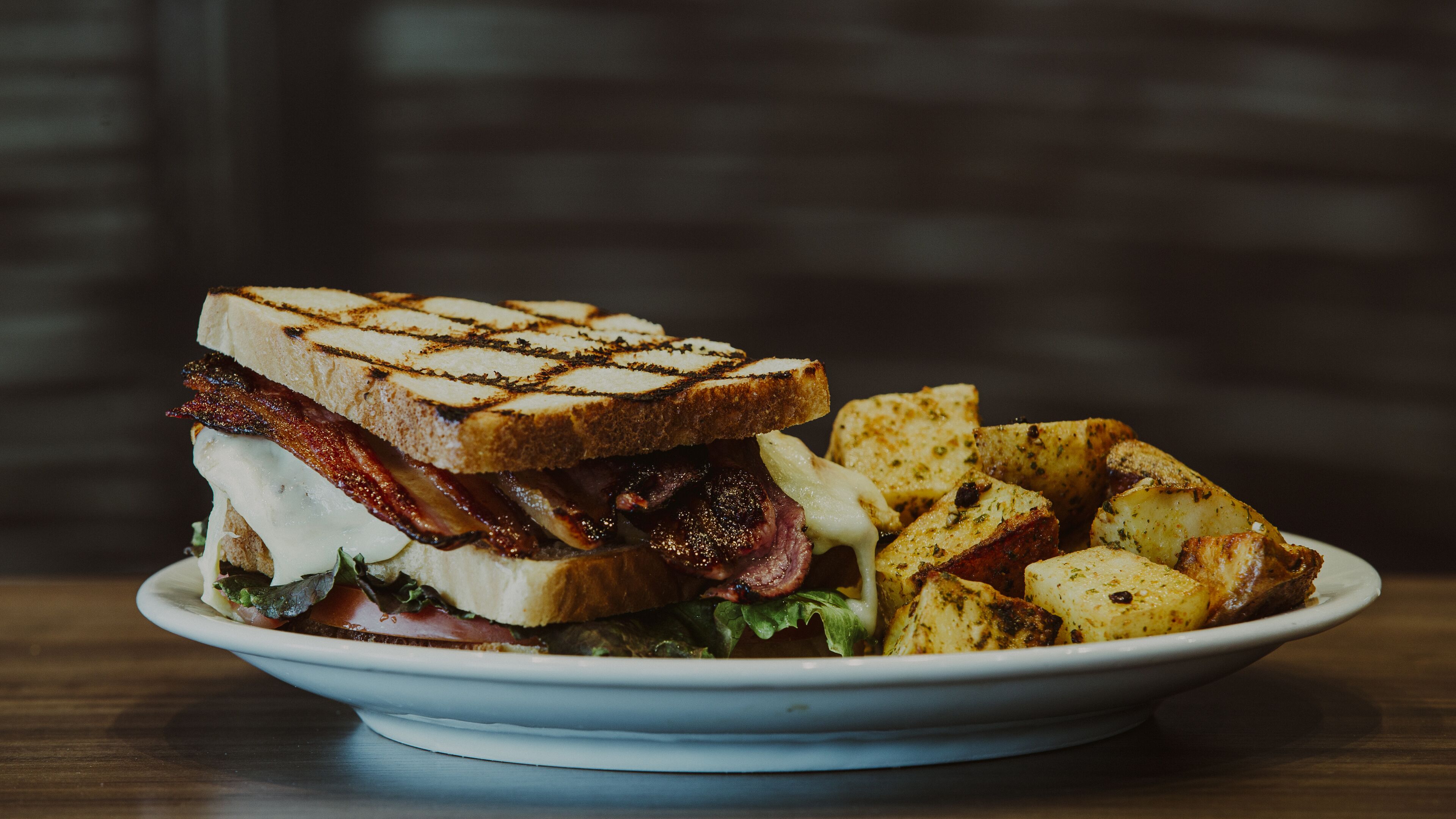En tallerken med grillstegt sandwich og ristede kartofler.