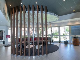 Un interior moderno con una zona de estar, columnas de madera y un amplio ventanal que proporciona luz natural.