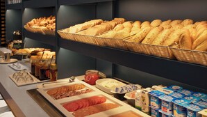 Un bufé con diversas opciones de comida, incluyendo pan, pasteles, carnes y productos lácteos.