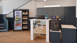 Zona de recepción con tienda de B&B, quiosco de autoservicio y nevera llena de bebidas.