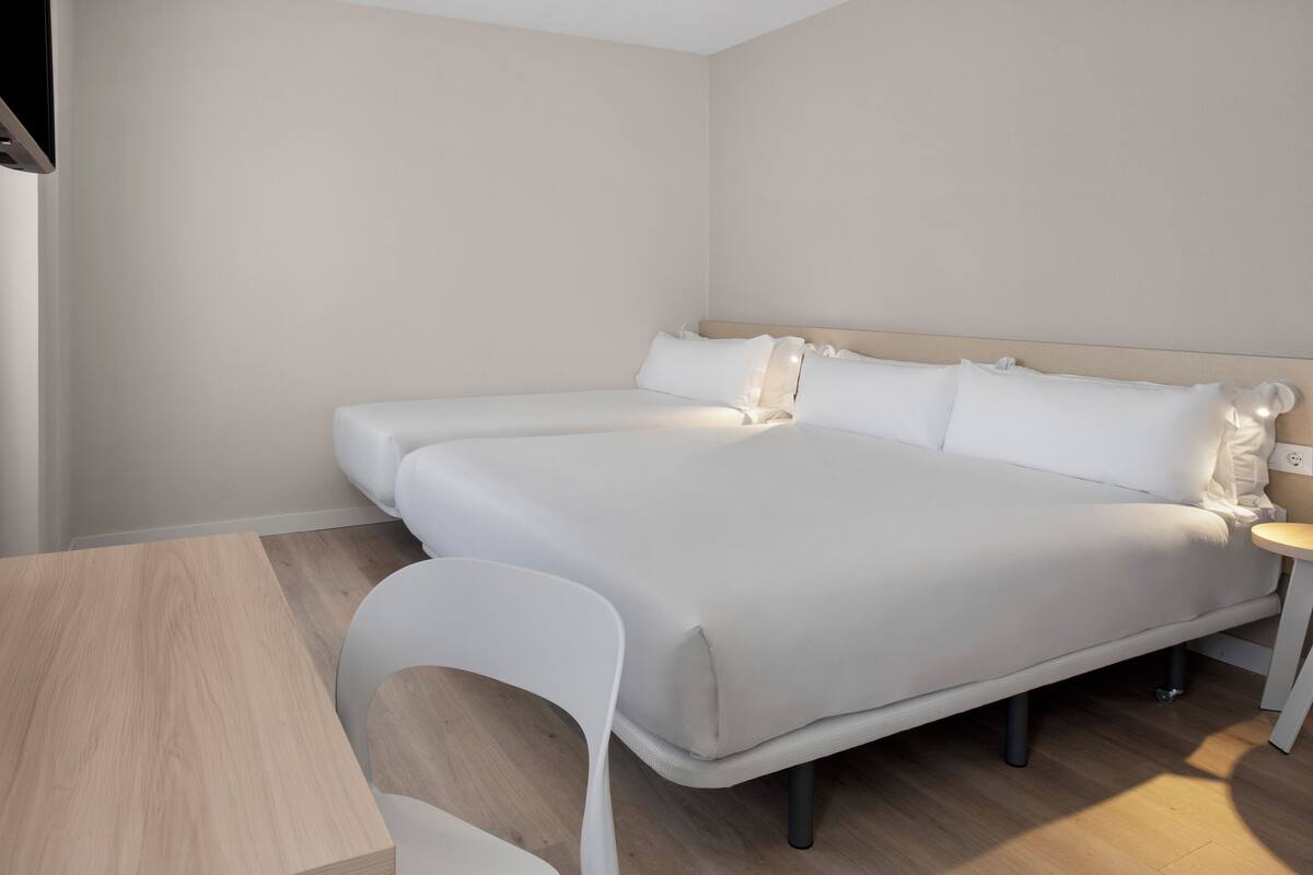 Una habitación de hotel moderna con una cama grande, una mesita y una silla.