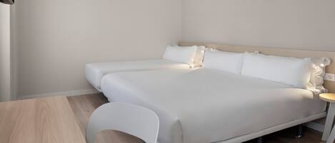 A modern hotel room with a large bed, a small table, and a chair.