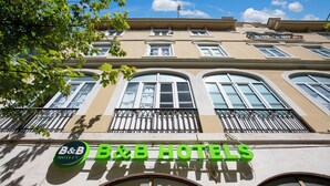 Fachada de hotel con un letrero que dice "B&B HOTELS" y un balcón con barandillas de metal.