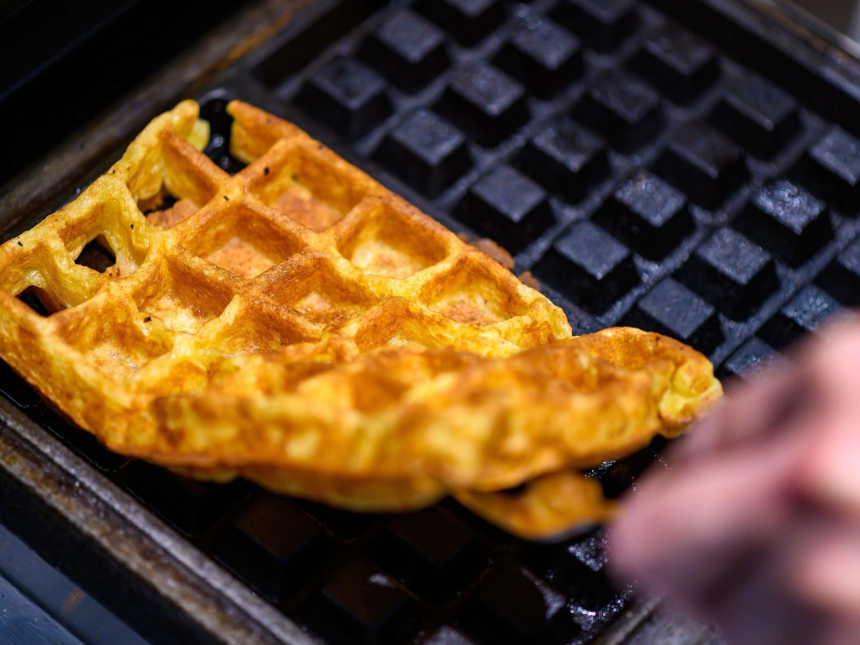 A waffle being cooked on a griddle.