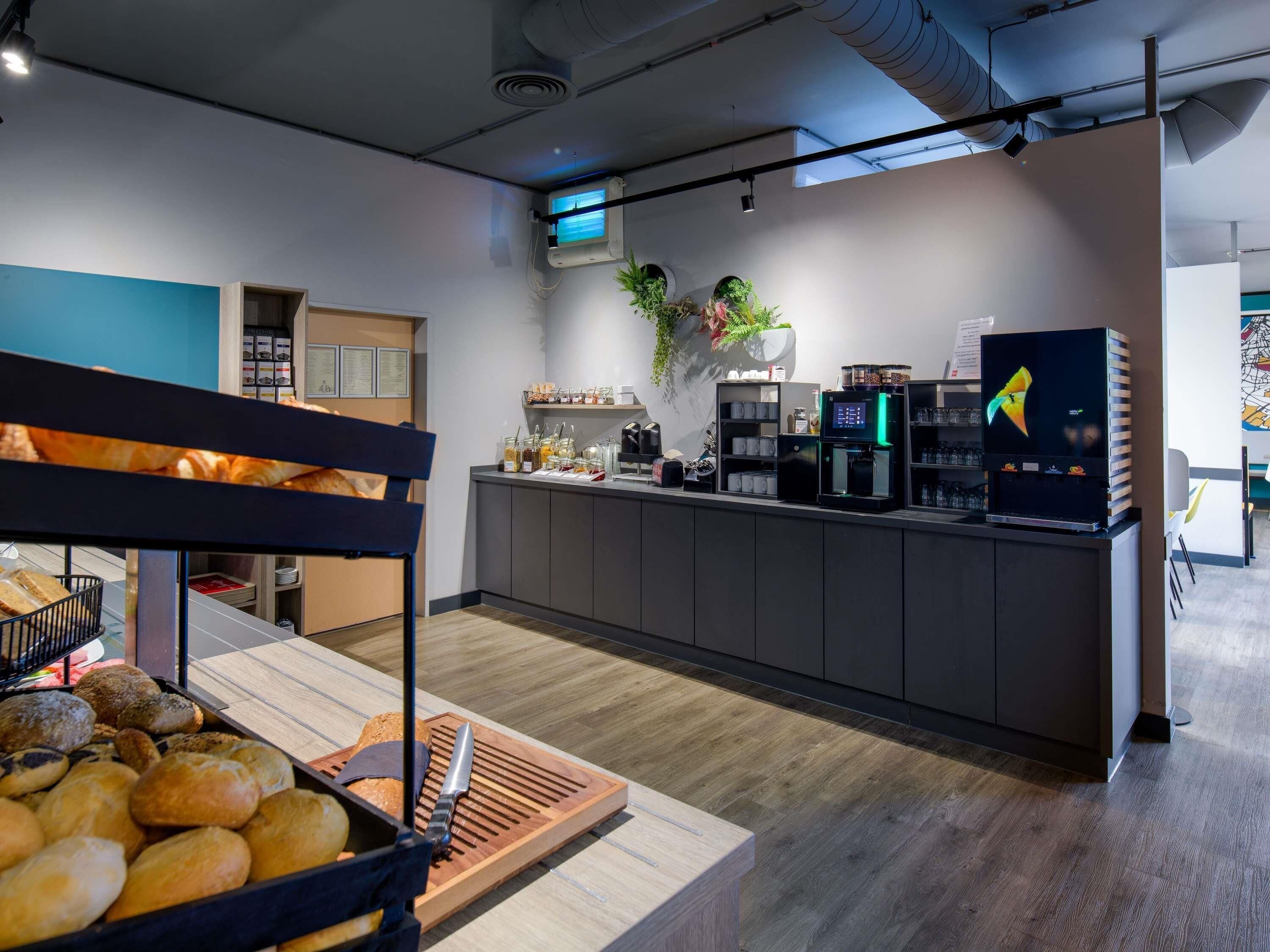A modern café with a counter, coffee machines, and a variety of baked goods.
