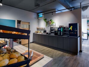 A modern café with a counter, coffee machines, and a variety of baked goods.