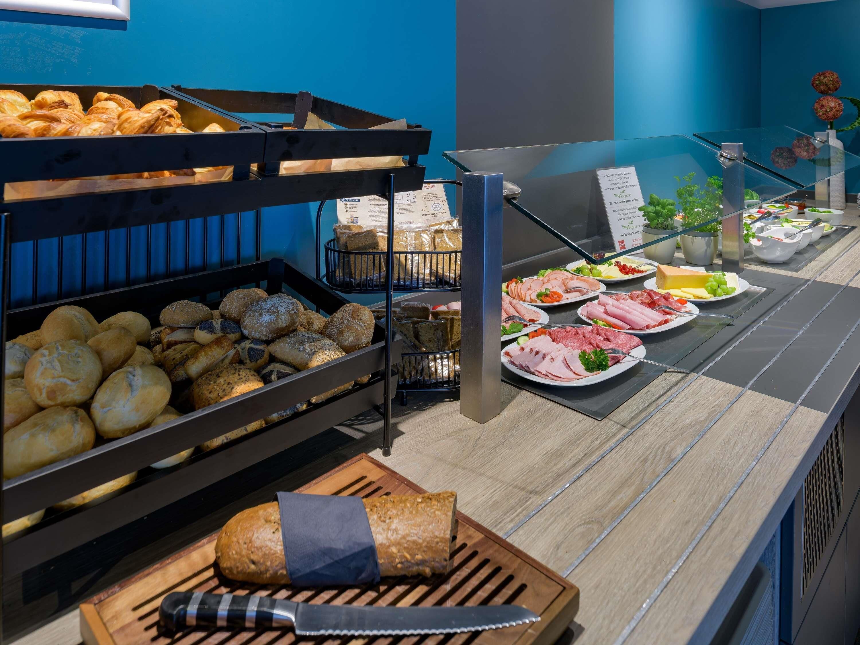 Un buffet proposant une variété de pains, de viennoiseries, ainsi qu’un assortiment de viandes et de fromages.