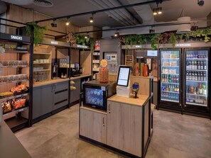 A modern café interior with snack shelves, a coffee station, and beverage dispensers. - ibis Köln Frechen (Frechen)