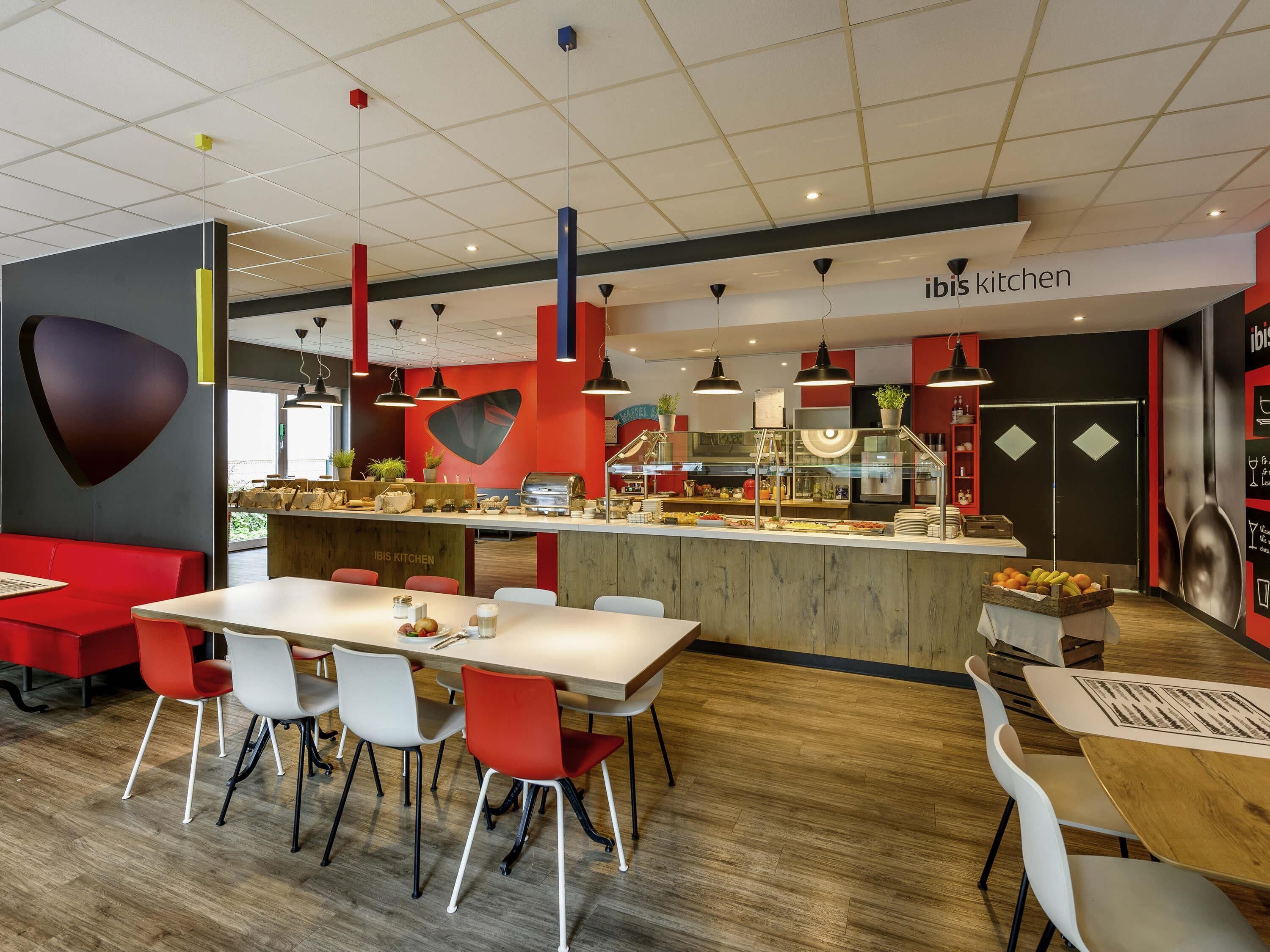 Un interior de restaurante moderno con una barra central, zona de estar y cocina a la vista.