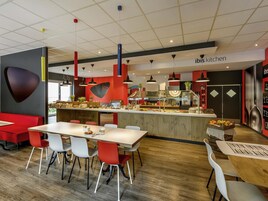 Un interior de restaurante moderno con una barra central, zona de estar y cocina a la vista.