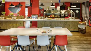 A modern kitchen area with a counter, seating, and a sign reading 'IBIS KITCHEN'.