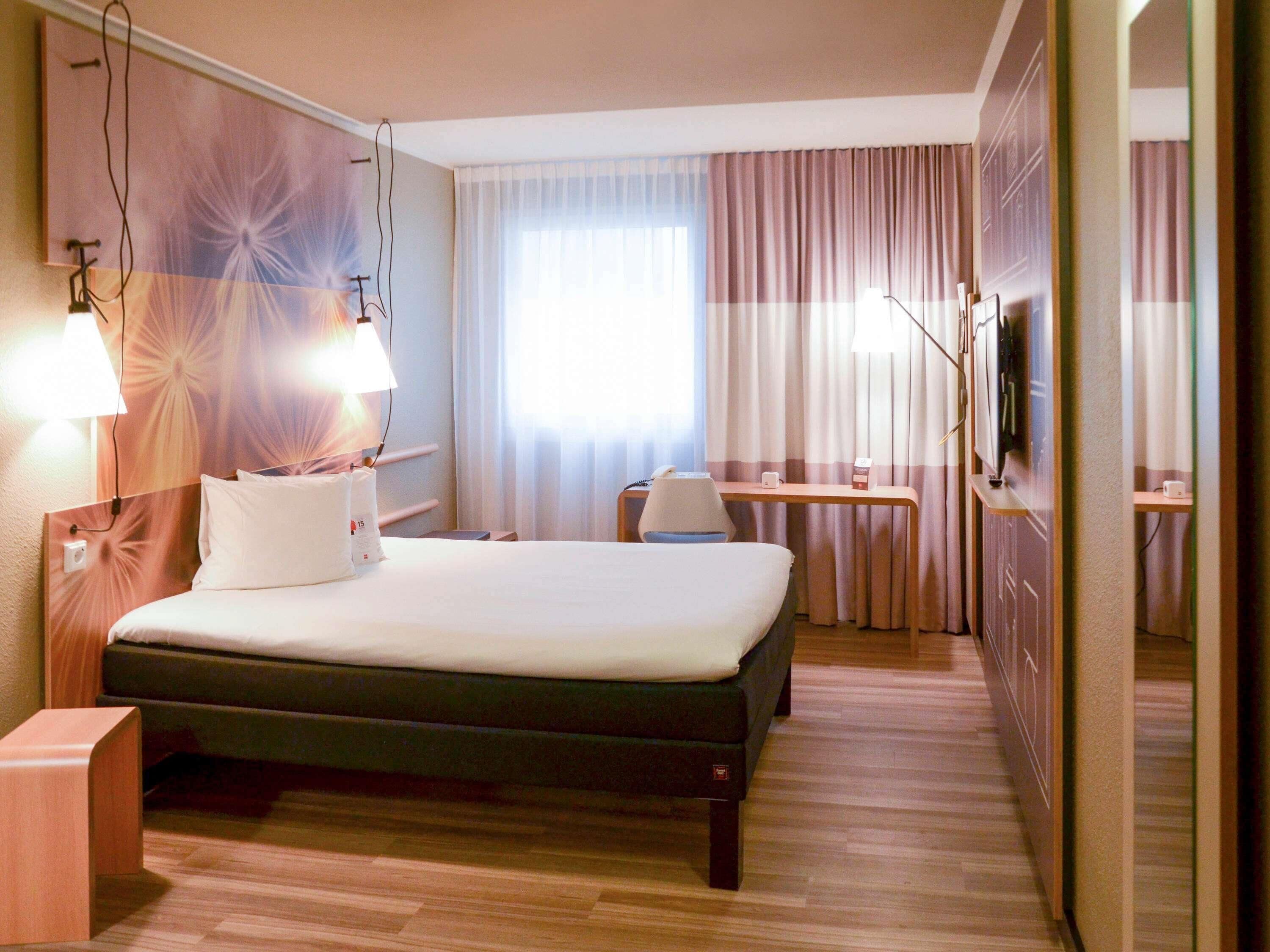 Ein Hotelzimmer mit Bett, Schreibtisch, Stuhl und Fernseher.