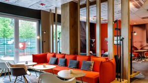 A modern interior with a red sofa, white chairs, and a wooden floor.