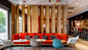 A modern interior with a red sofa, round tables, and wooden columns.