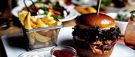 A burger with fries and ketchup on a white plate.