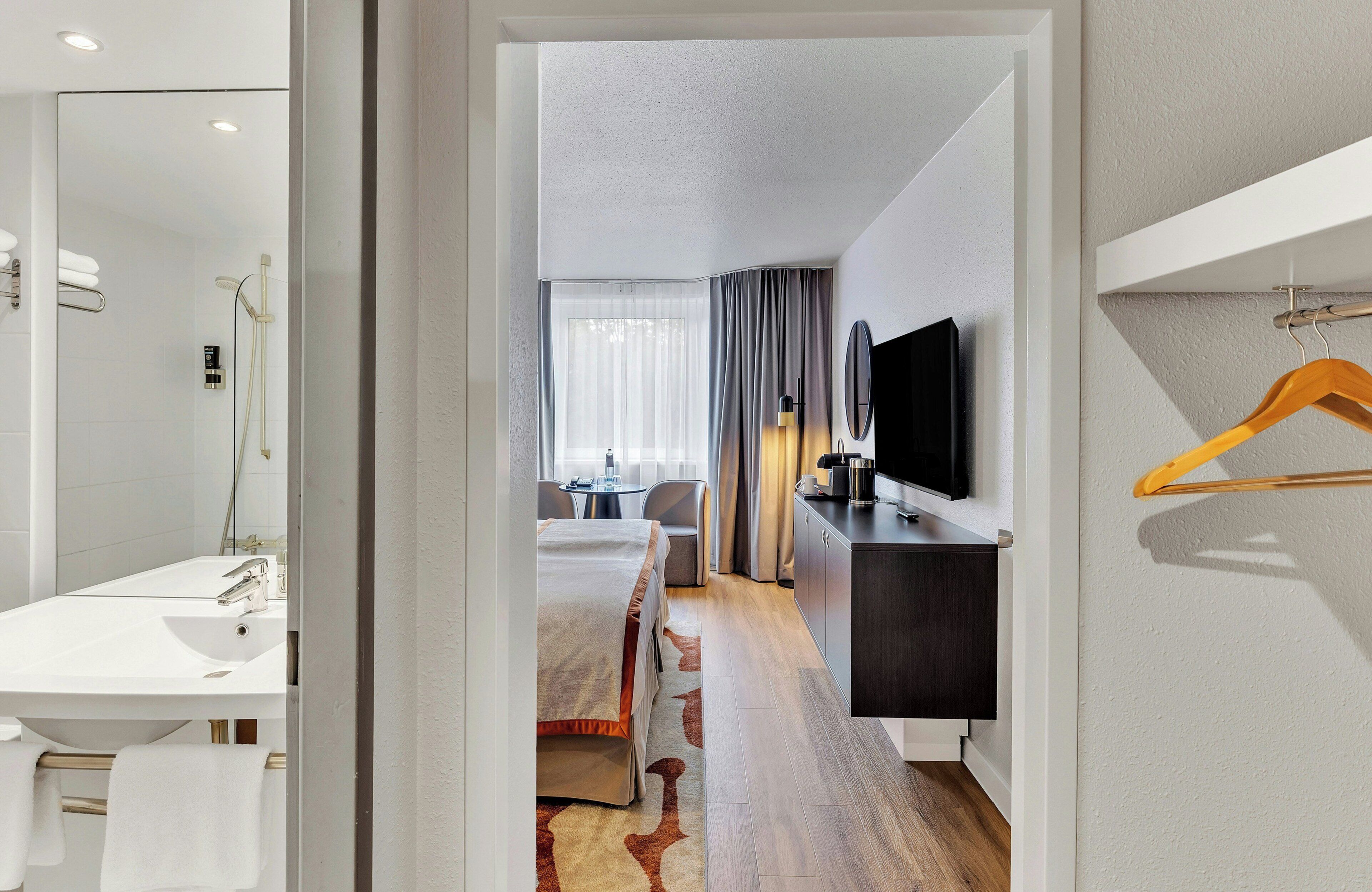 A hotel room with a bed, a desk, a television, and a bathroom.