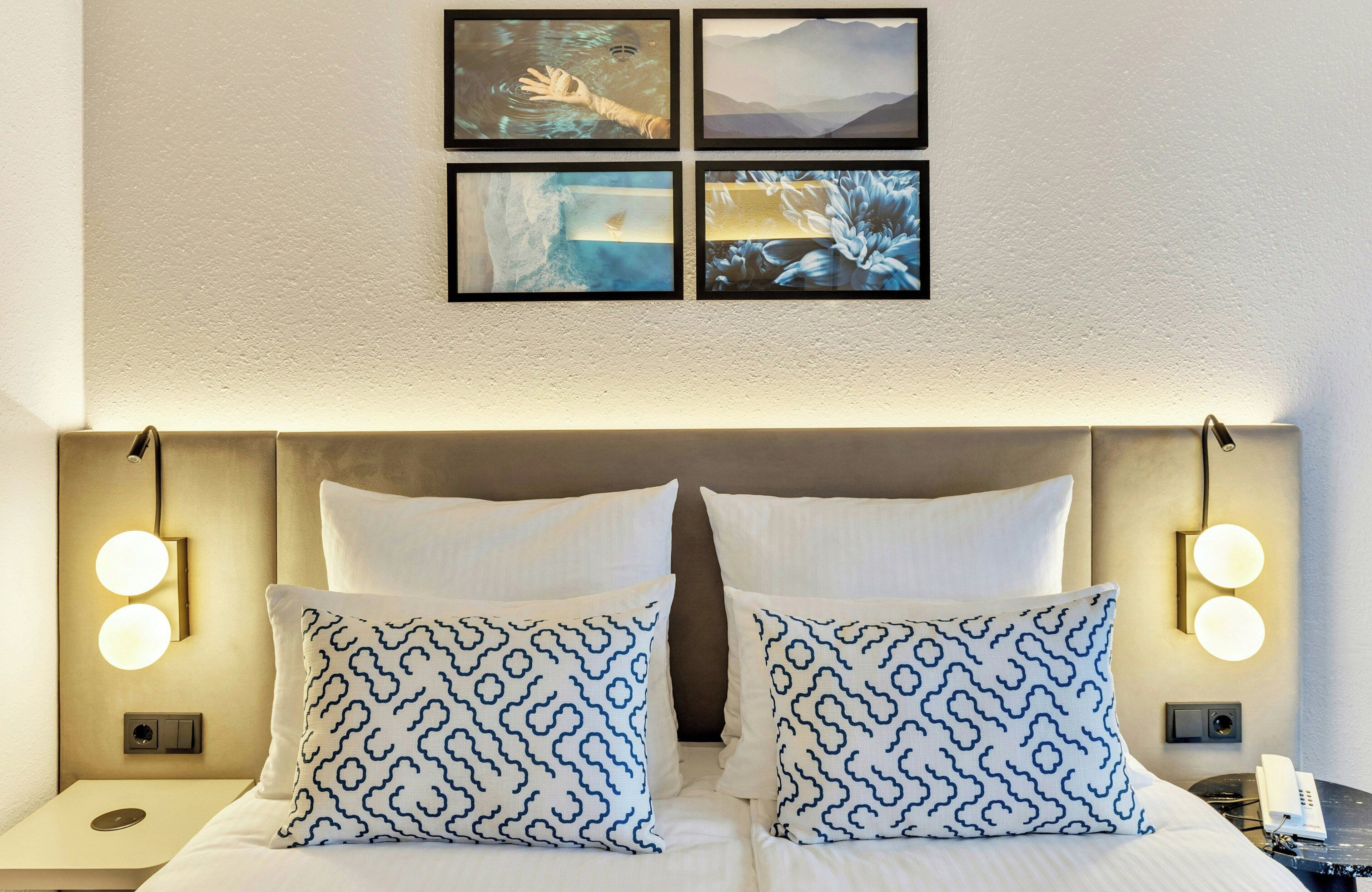 A hotel room with a large bed, two bedside tables, and four framed pictures on the wall.